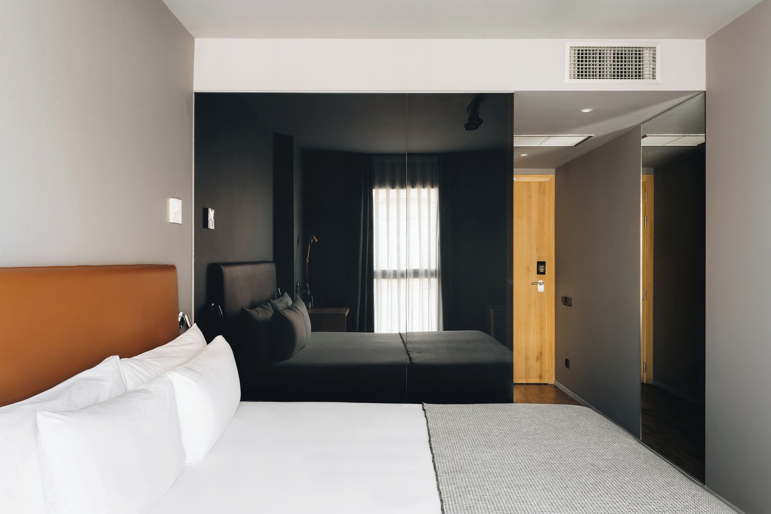 Una habitación de hotel con cama, sofá, escritorio y ventana con cortinas.