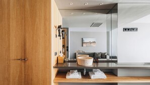 Une salle de bain moderne avec une porte en bois, un lavabo doté d’un grand bac, un miroir et un porte-serviettes.