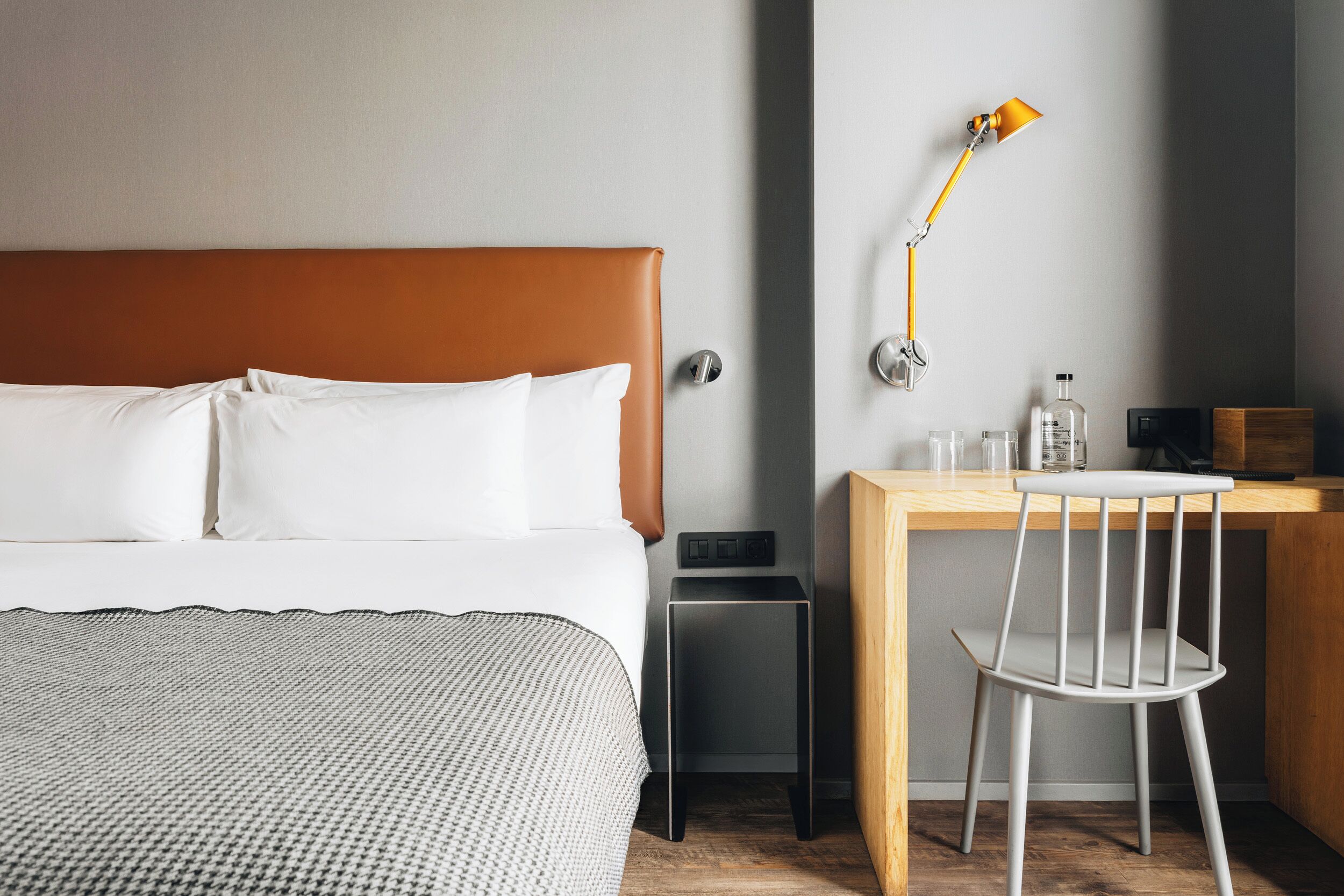 Une chambre d’hôtel comprenant un lit, une table de chevet, une lampe, une chaise et un petit bureau avec une chaise.