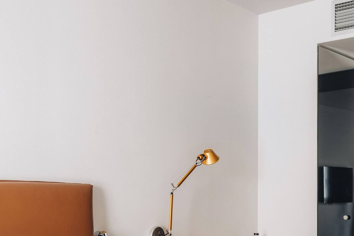 Een hotelkamer met een bed, een bureau met stoel, een lamp en een televisie aan de muur.