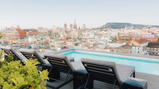 Une piscine sur le toit, dotée de chaises longues et offrant une vue sur la ville.
