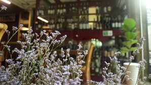 A library interior with bookshelves and a floral arrangement in the foreground. - Crown Diamond Hotel (Ho Chi Minh City)