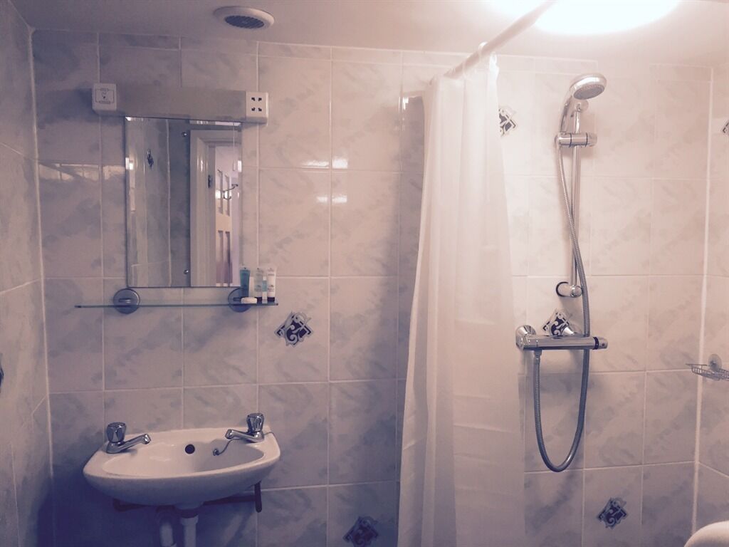 A bathroom with a sink, mirror, and shower.