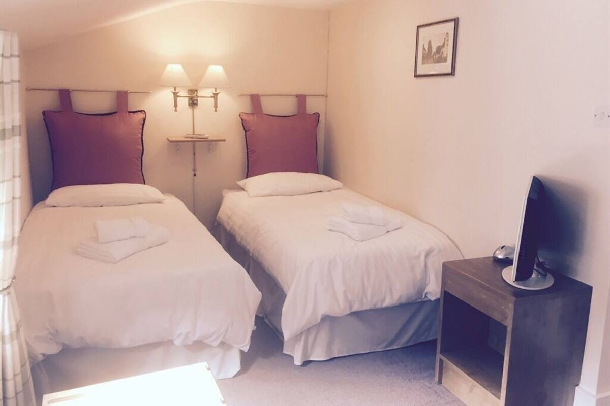 A hotel room with two beds, a TV, and a bedside table.