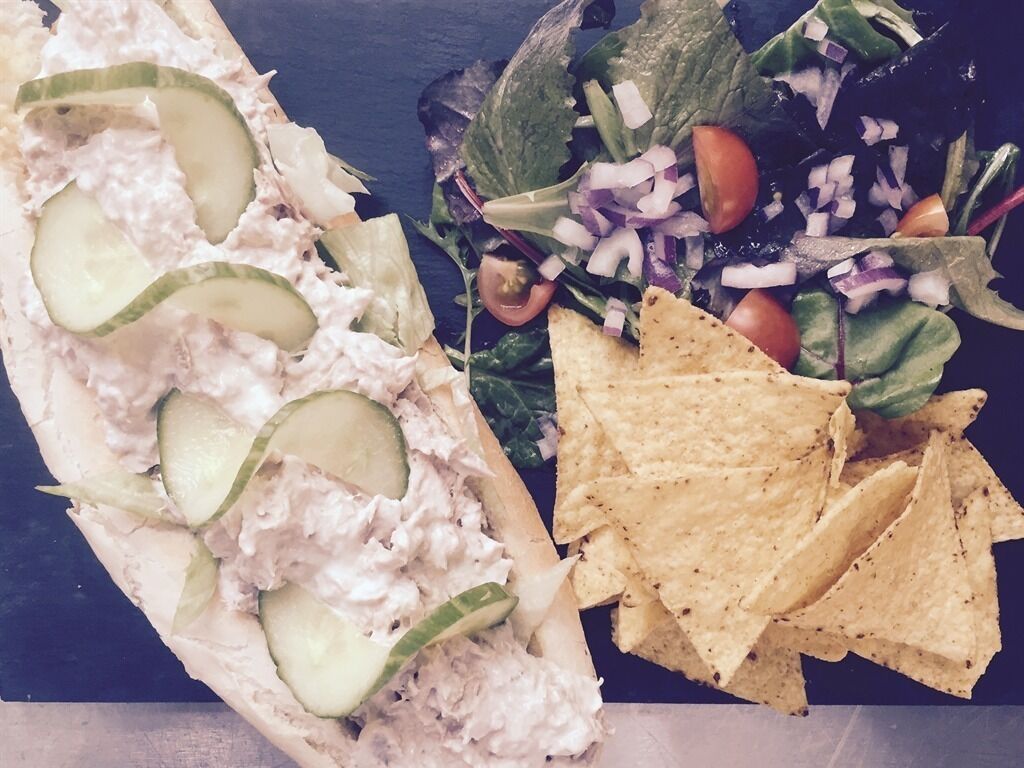 Un sandwich aux tranches de concombre, accompagné d’une salade et de chips de tortillas.