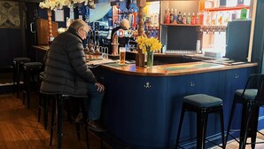 A bar area with a wooden floor, a blue counter, and stools. - The Globe Inn (Buckfastleigh)