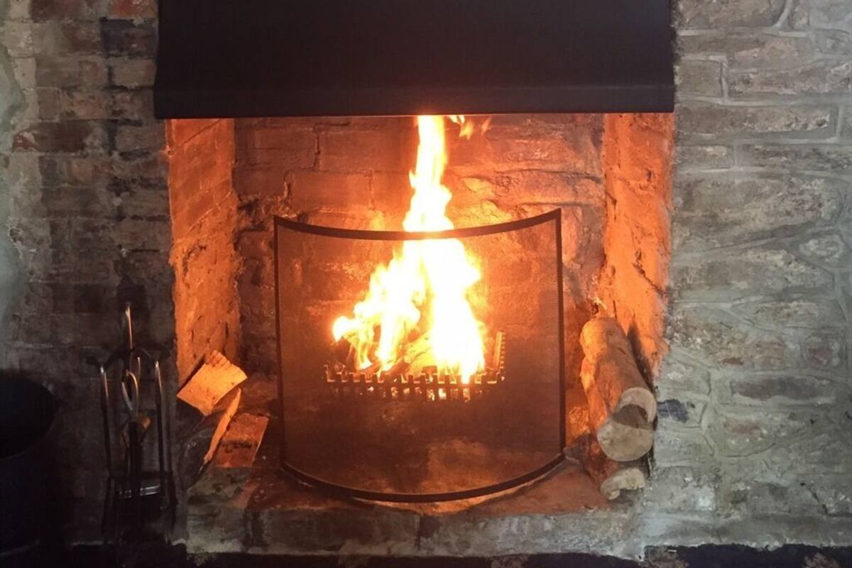 A fireplace with a fire burning inside, set in a stone wall.
