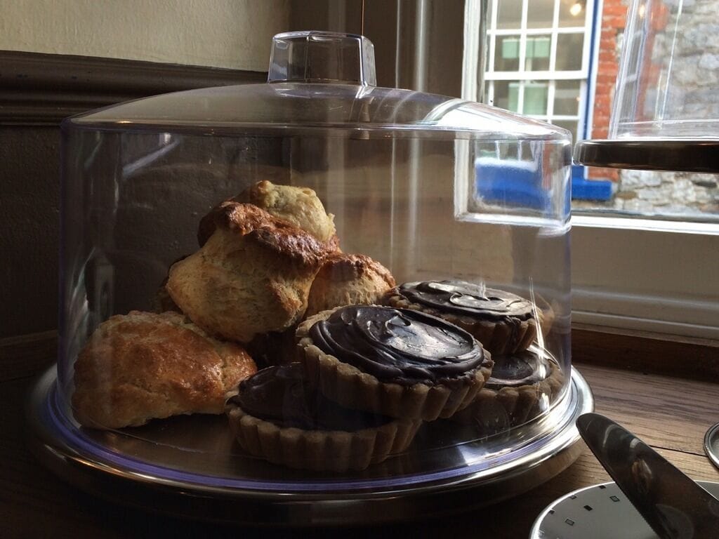 A dessert display with a glass dome cover, including pastries and chocolate tarts.