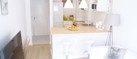 Eine moderne Küche mit weißen Schränken, einer Holz Arbeitsplatte und zwei Barhocker.