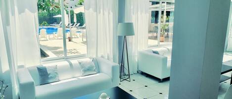 Ein modernes Wohnzimmer mit einer Couch, einem Couchtisch und Blick auf einen Poolbereich.
