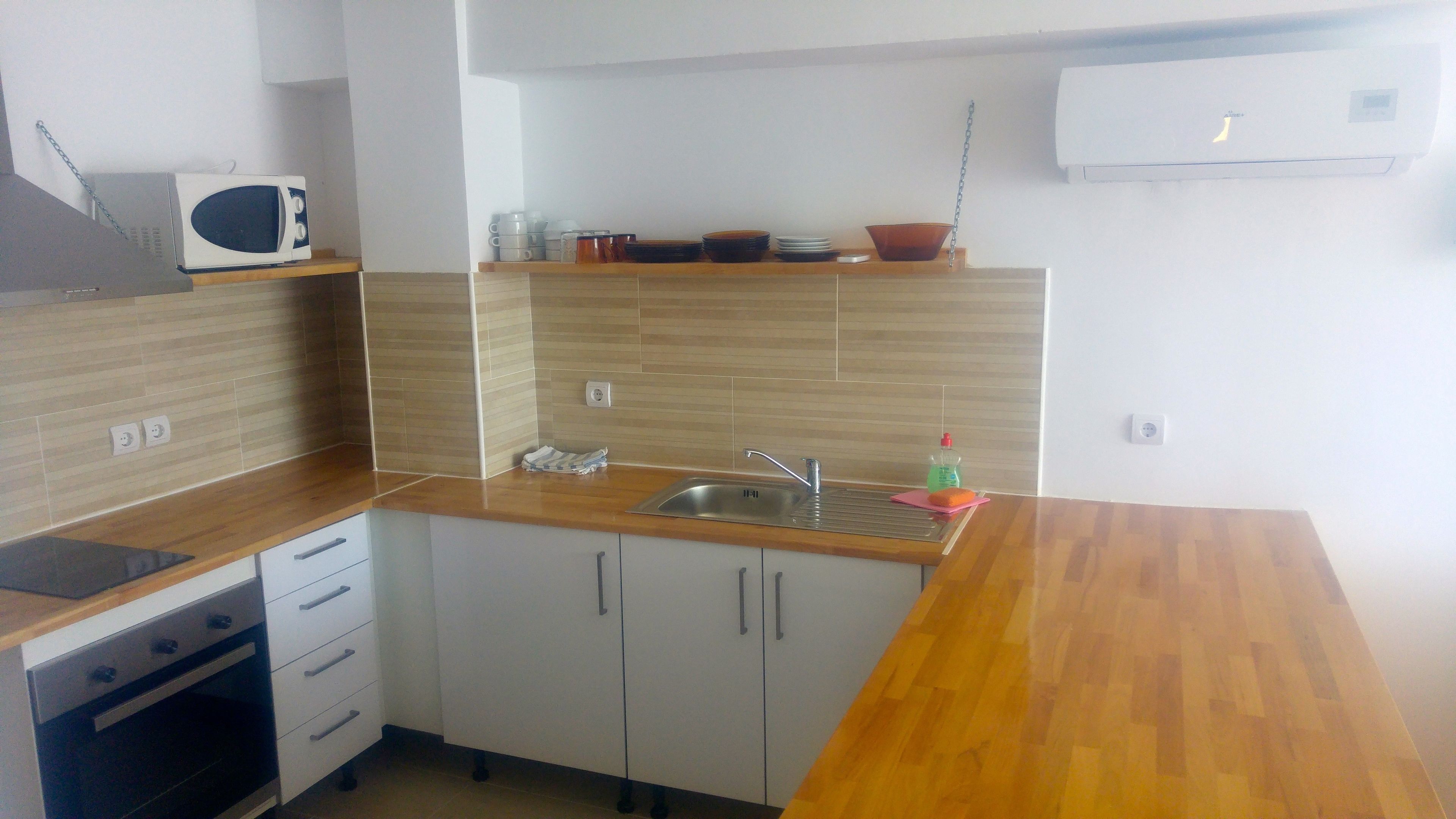 A compact kitchen with a wooden countertop, a built-in sink, and a microwave.