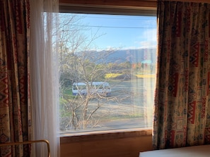 A room with a large window, patterned curtains, and a view of a road with a vehicle. - Okubiwako Makino Grand Park Hotel (Takashima)