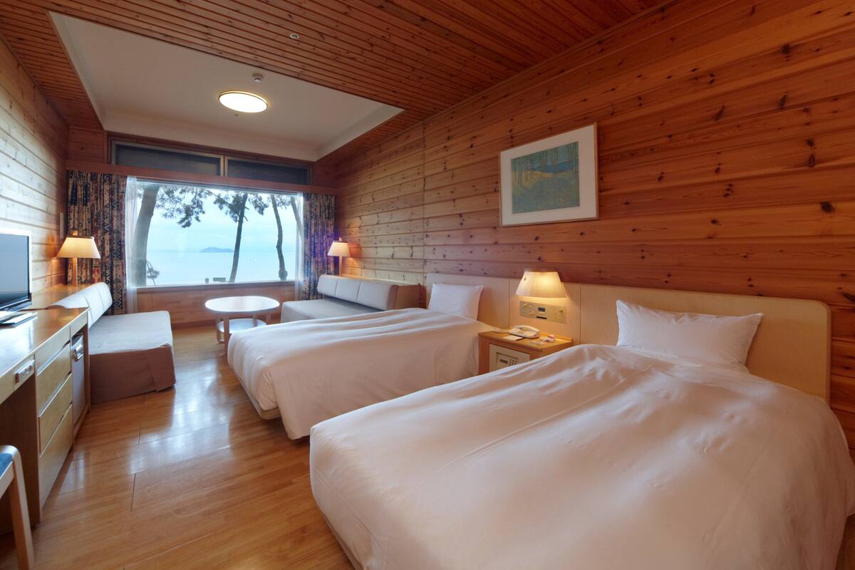 Uma cabana com duas camas, uma escrivaninha e vista para o mar.