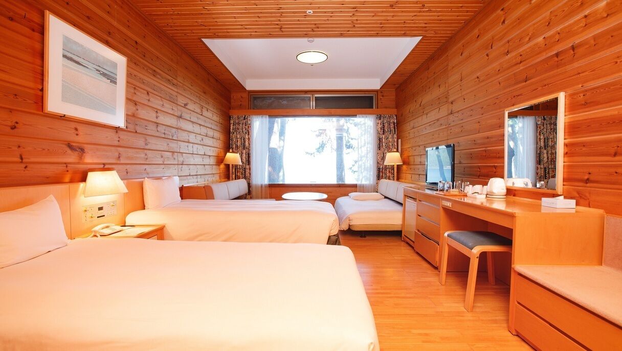 Una habitación tipo cabaña con dos camas, un escritorio, una silla y un televisor.