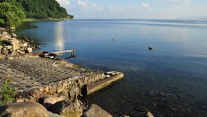 A calm lake with a rocky shoreline and a wooden dock extending into the water. - Okubiwako Makino Grand Park Hotel (Takashima)