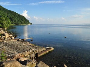 A calm lake with a rocky shoreline and a wooden dock extending into the water. - Okubiwako Makino Grand Park Hotel (Takashima)