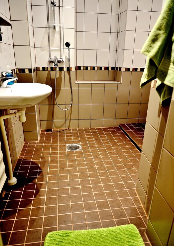 A bathroom with a sink, shower, and tiled floor. - Hostel Diana Park (Helsinki)