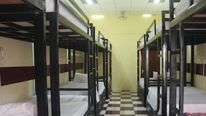 A corridor with bunk beds arranged on either side, checkered flooring, and a ceiling fan. - The Local Riverside (Phnom Penh)