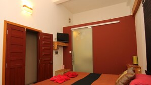 A bedroom with a bed, a TV mounted on the wall, a wardrobe, and a small wooden cabinet. - The Local Riverside (Phnom Penh)