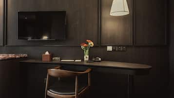 A modern bar area with a flat-screen TV mounted on the wall, a vase with flowers on the counter, and a pendant light above.