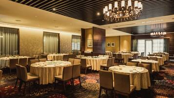Un salón de conferencias de hotel con mesas redondas, sillas y una araña.