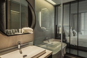Une salle de bain moderne dotée d’un grand miroir, de deux vasques et d’une douche séparée par une paroi en verre.