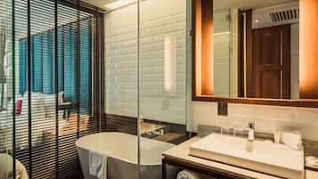 Un baño moderno con una bañera independiente, un espejo grande y un separador de vidrio.