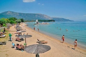Ein Strand mit Sonnenschirmen, Liegestühlen und badenden Personen.