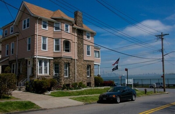 A two-story house with a stone facade, a chimney, and a view of the water. - The Harbor House Bed & Breakfast (Staten Island)