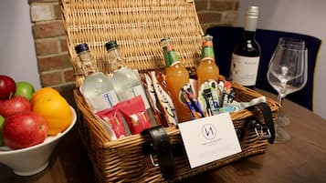 A wicker basket filled with various items including bottles, a wine glass, and a bowl of fruit.