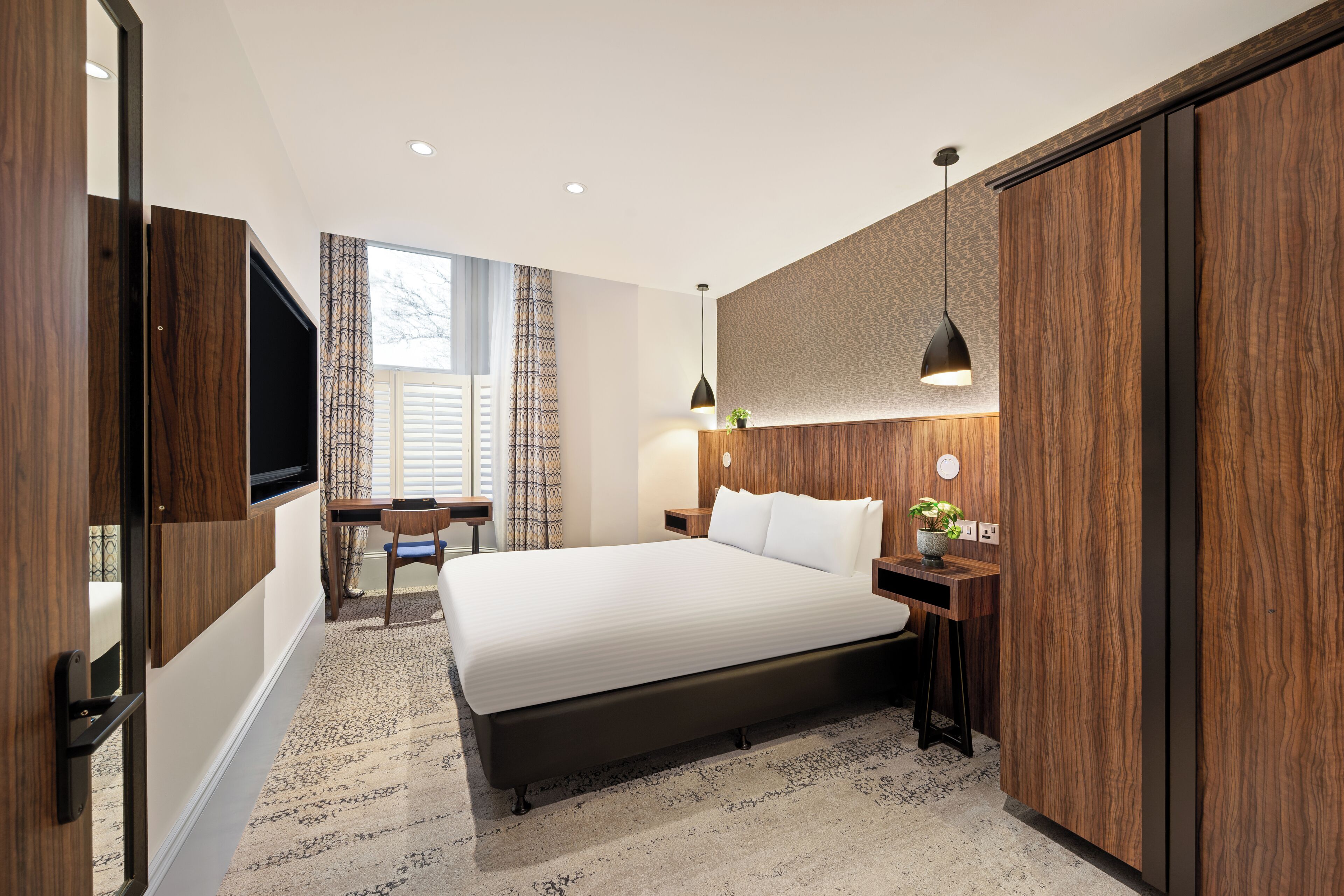 Un dormitorio moderno con una cama grande, un escritorio y un televisor.