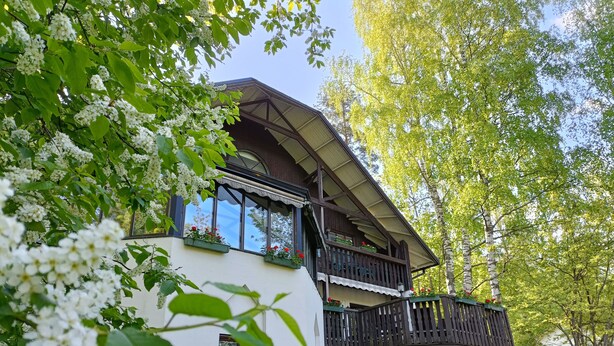 Een gebouw met twee verdiepingen, een balkon, grote ramen en een witte gevel.