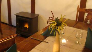 A dining table set for two with a vase of flowers, candles, and wine glasses.