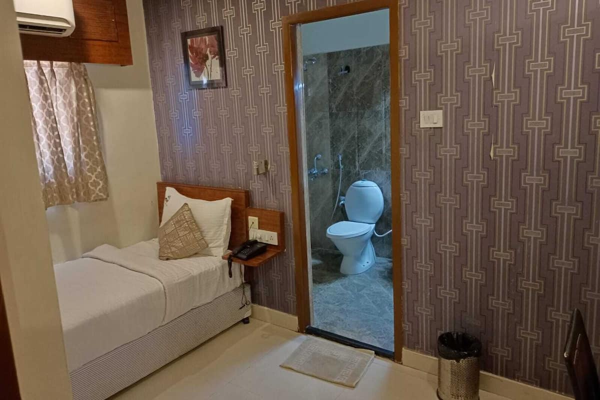 A compact bedroom with a bed, bedside table, and a small window with curtains.