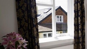 A room with a window, a vase with flowers, and a radiator. - Royal Oak (Kingsbridge)