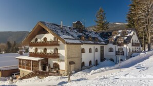 A large, multi-story building with a snow-covered roof, stone walls, and multiple balconies. - Wellness Hotel Windsor (Spindleruv Mlyn)
