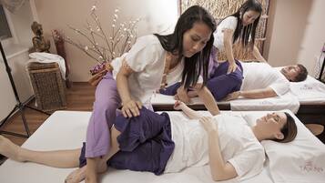 A massage therapy session in a room with a wooden floor, a statue, and a decorative wall.