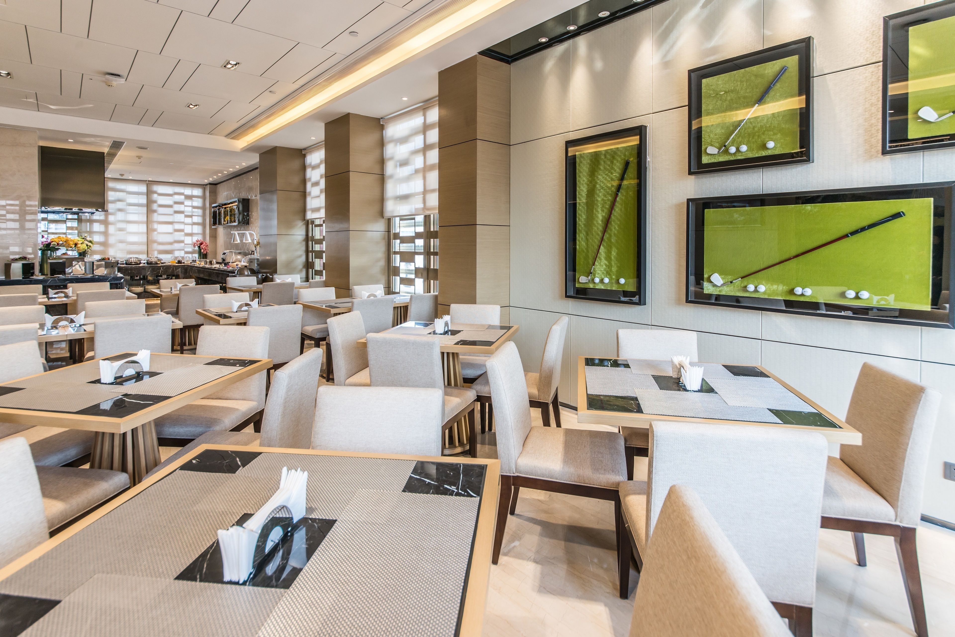 Un espace repas moderne, doté de plusieurs tables et chaises, d’un bar et d’un grand écran diffusant un match de golf.