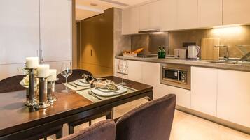 A modern kitchen with a dining area, featuring a built-in microwave, a coffee maker, and a bread basket on the counter.