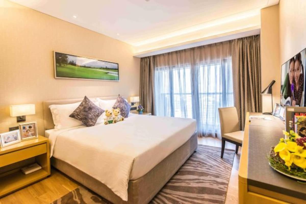 A hotel room with a large bed, a desk, a chair, a TV, and a painting on the wall.