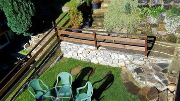 A patio area with a stone wall, a wooden deck, and a seating arrangement with chairs and a table.