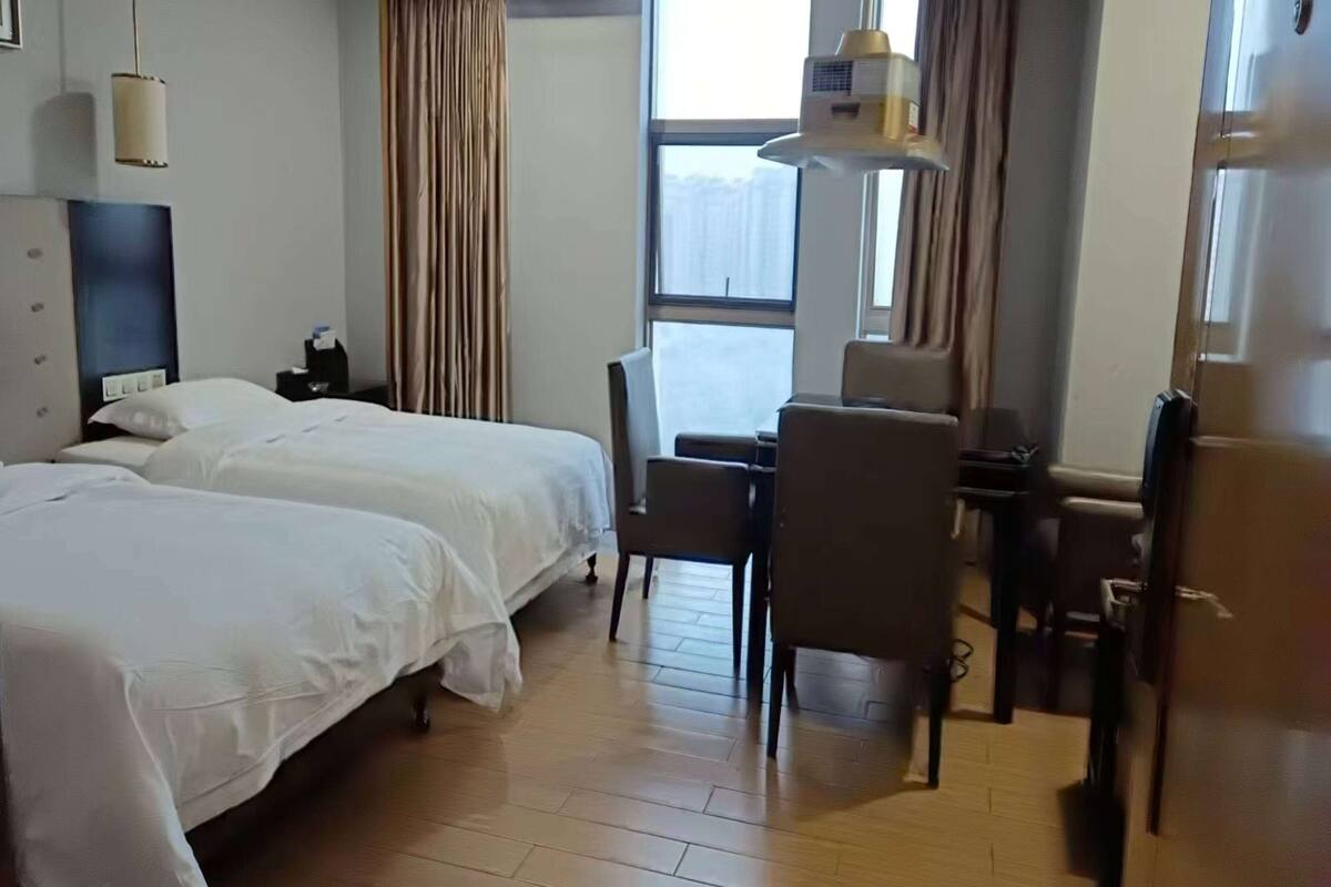 Une chambre d’hôtel avec deux lits, un bureau et une chaise.