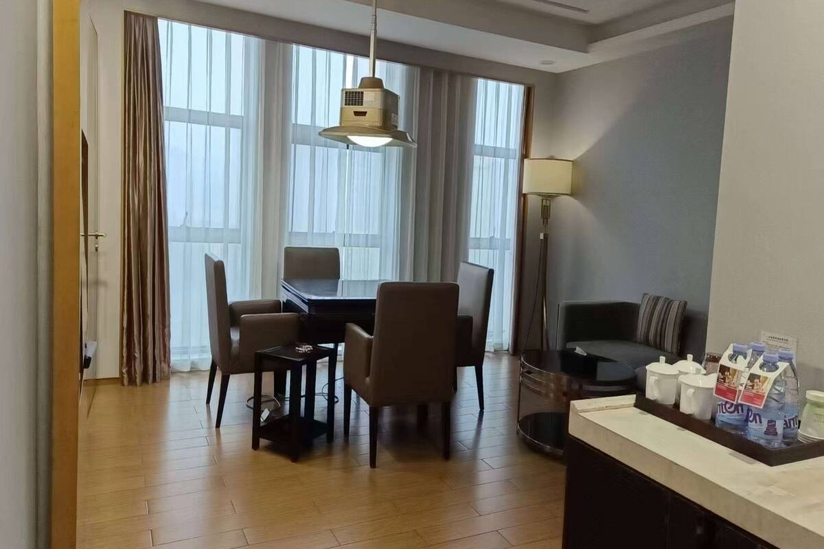 Une chambre d’hôtel comprenant un coin repas, un canapé, une lampe et un distributeur d’eau posé sur le comptoir.