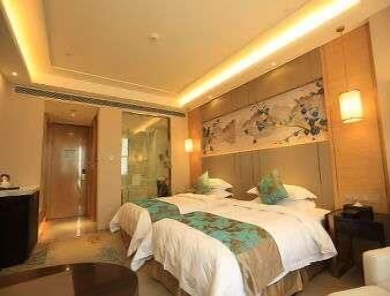 Une chambre d’hôtel comprenant un lit, des tables de chevet, un miroir et une œuvre d’art accrochée au mur.