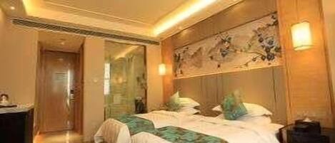 Une chambre d’hôtel comprenant un lit, des tables de chevet, un miroir et une œuvre d’art accrochée au mur.