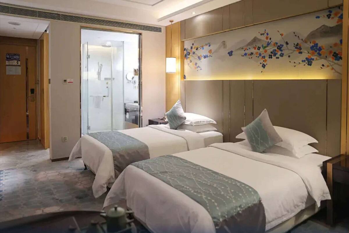 Une chambre d’hôtel avec deux lits, une salle de bain et un mur décoratif.