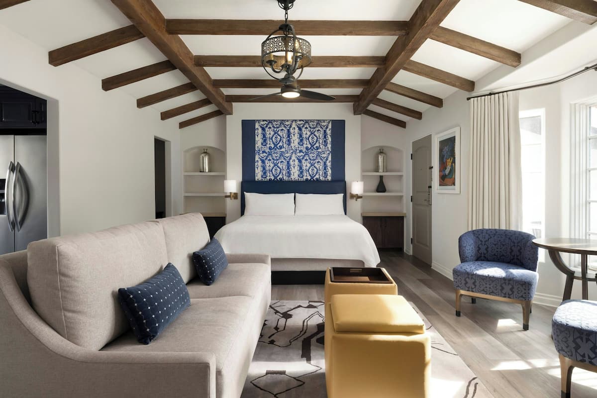 A modern bedroom with a large bed, a sofa, a chair, and a small table.