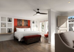 A bedroom with a bed, a ceiling fan, a red accent wall, and a view of the outside.