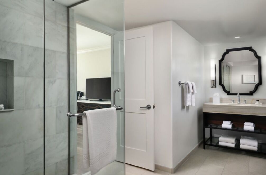 Een moderne badkamer met een douchecabine van glas, een wit wastafelmeubel met spiegel en een handdoekhouder.