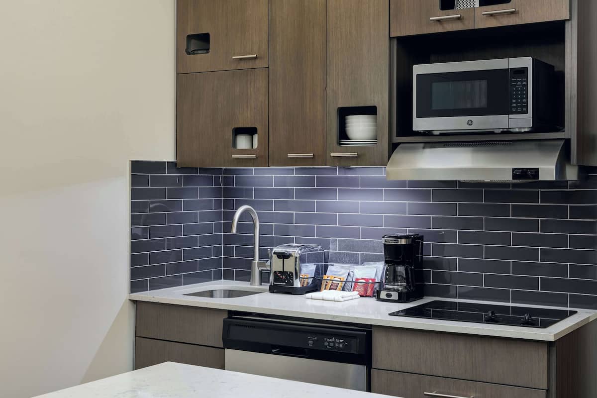 A modern kitchen with a built-in microwave, toaster, and coffee maker on the countertop.